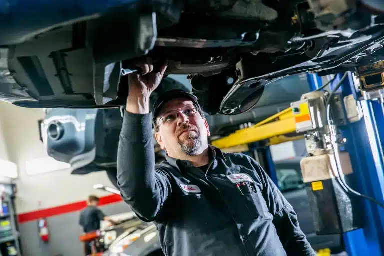 Ken's automotive and transmissions mechanic performing auto maintenance under car on lift