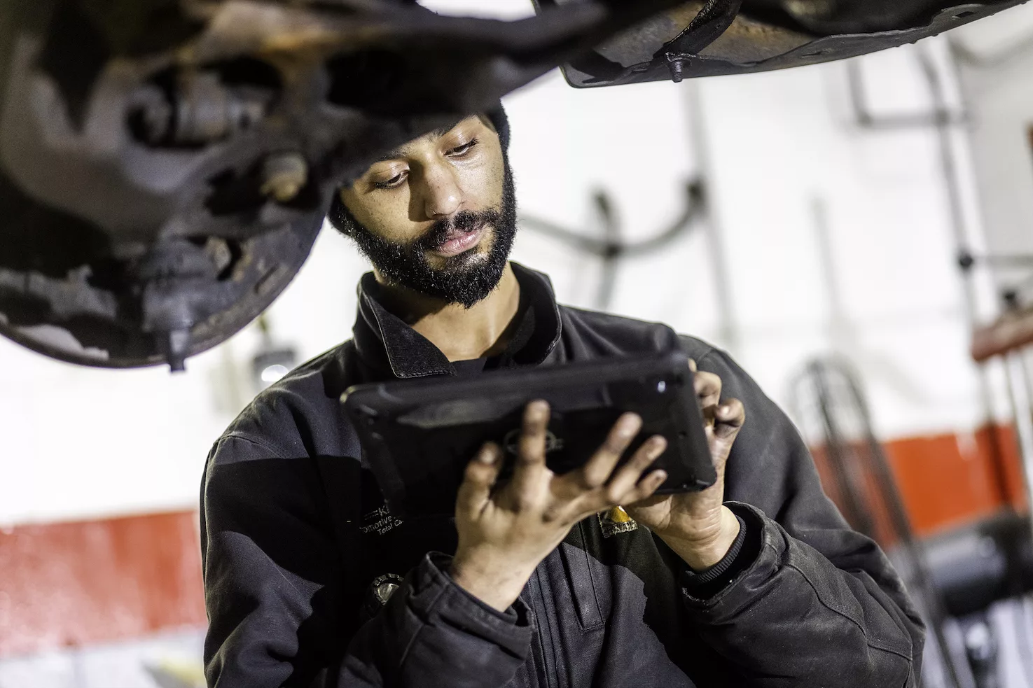 Ken's automotive and transmissions mechanic under car with computer