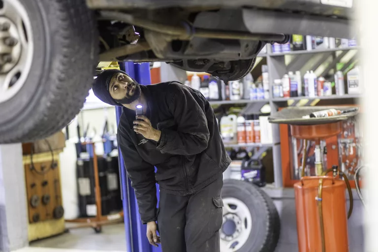 Ken's automotive and transmissions mechanic flash light under car