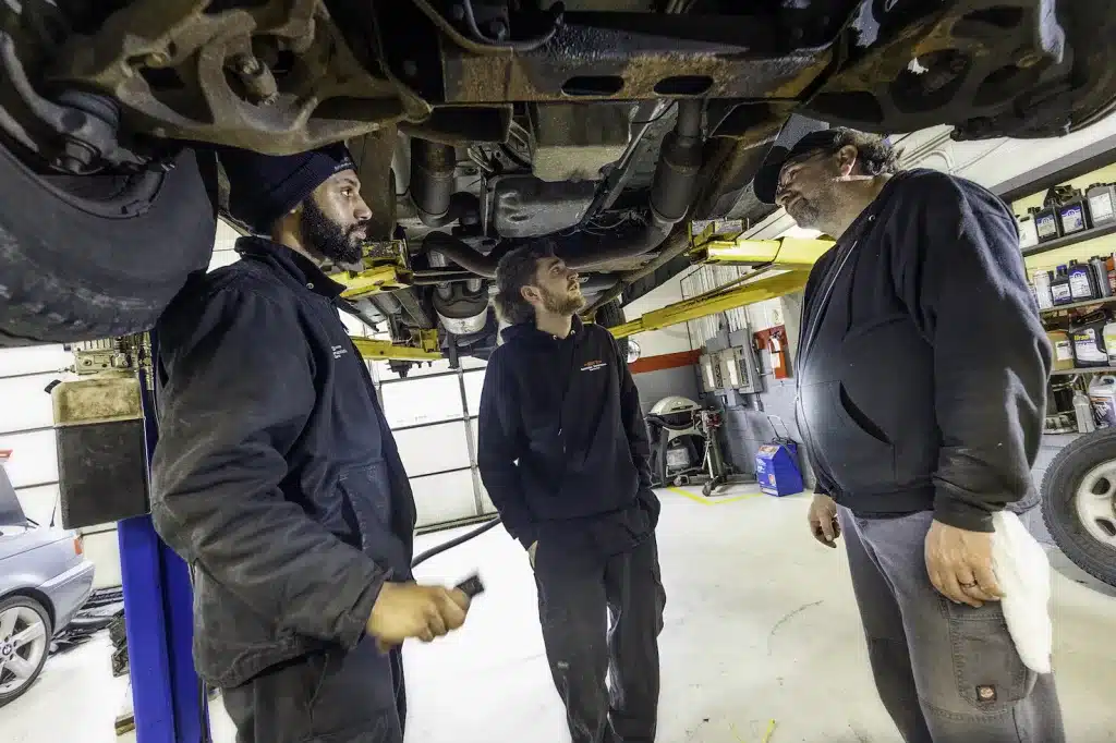 Ken's automotive and transmissions mechanics inspecting car on lift