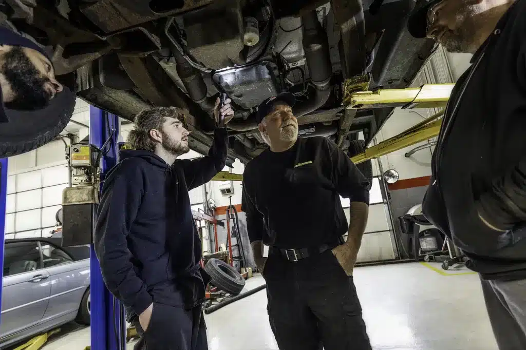 Ken's automotive and transmissions mechanics inspecting car on lift