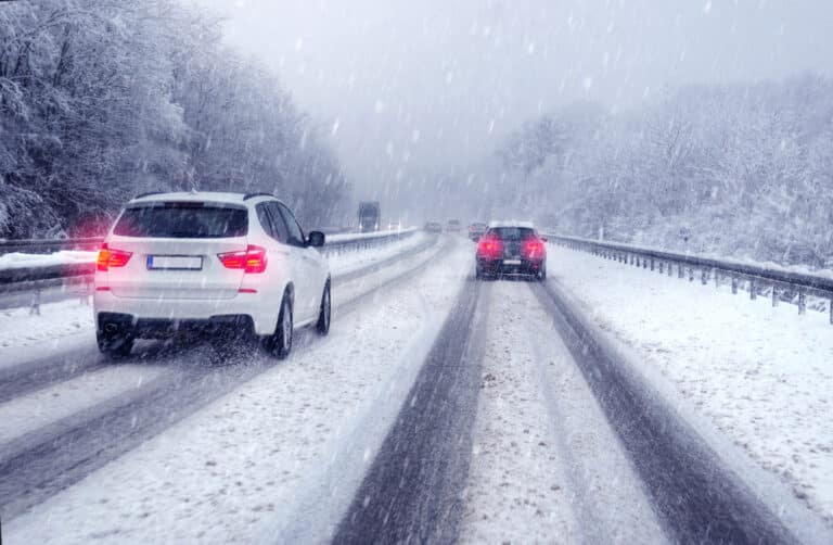 SUV car passing on a german highway with snow slush and snow fall, winter scenery